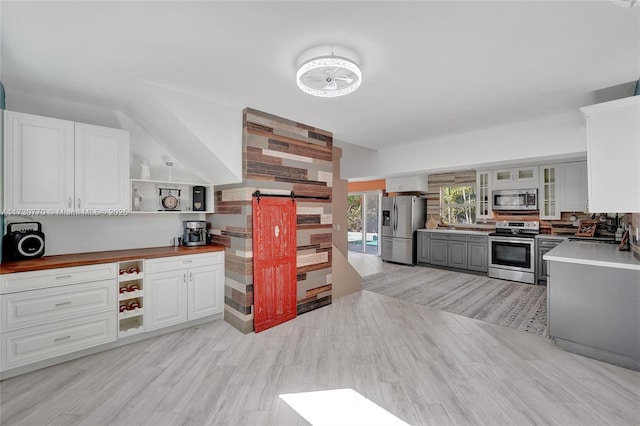 kitchen with stainless steel appliances, white cabinetry, light wood-type flooring, and butcher block countertops