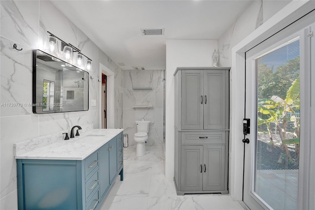 bathroom with vanity, tile walls, and toilet