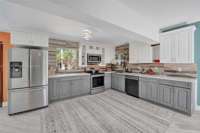 kitchen with white cabinetry, backsplash, stainless steel appliances, and gray cabinetry