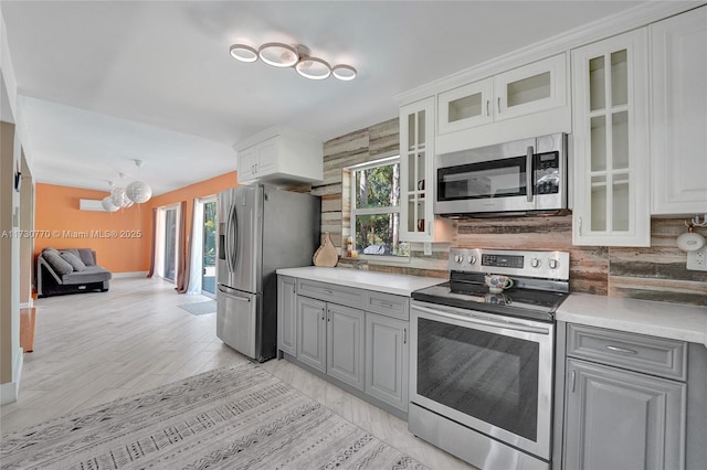 kitchen featuring a healthy amount of sunlight, gray cabinets, stainless steel appliances, and white cabinets