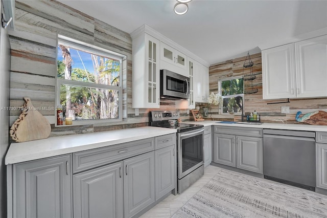 kitchen with gray cabinetry, stainless steel appliances, sink, and white cabinets