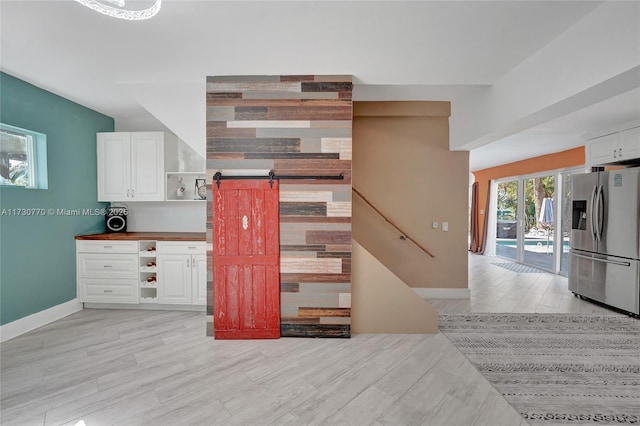 kitchen featuring white cabinetry, stainless steel fridge, a barn door, and light hardwood / wood-style floors