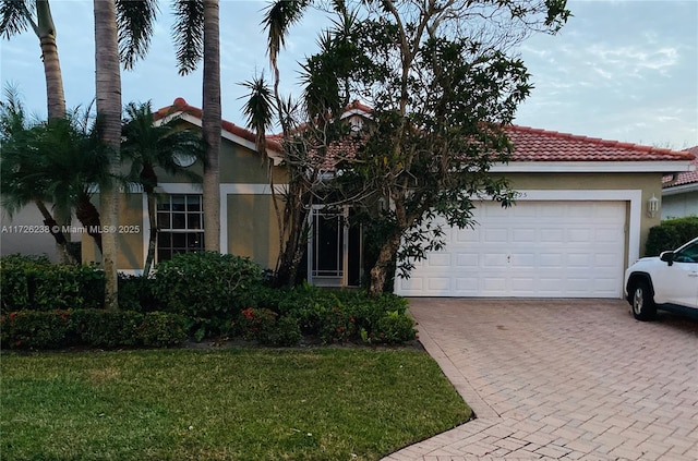 10495 S Utopia Cir S, Boynton Beach, FL 33437 - view of front facade featuring decorative driveway, a tiled roof, an attached garage, stucco siding, and a front lawn