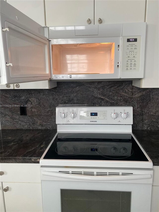 10495 S Utopia Cir S, Boynton Beach, FL 33437 - kitchen view of white appliances, backsplash, white cabinetry, and dark countertops