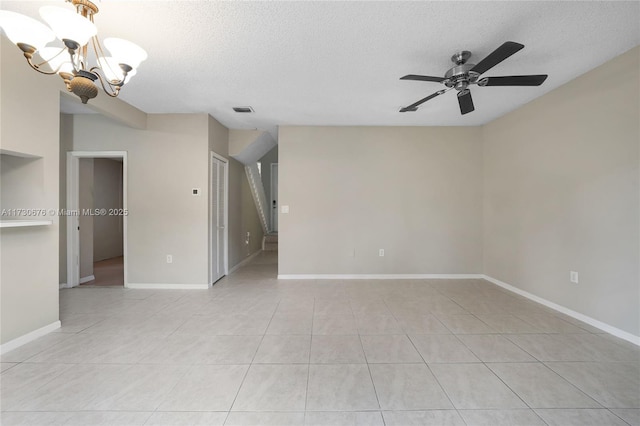 empty room featuring light tile patterned flooring, ceiling fan with notable chandelier, and a textured ceiling