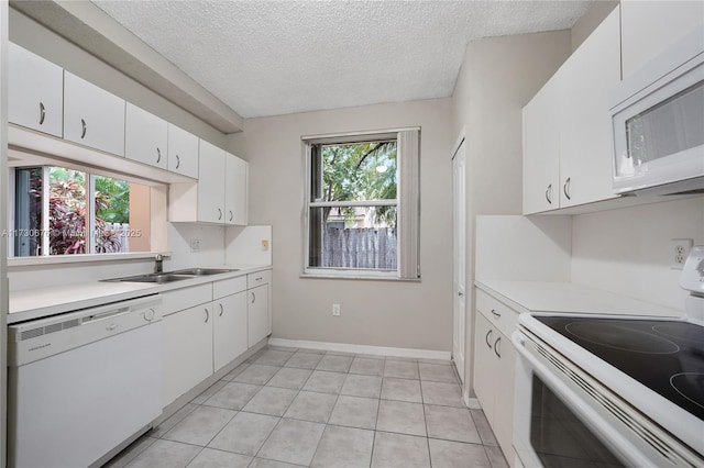 kitchen featuring sink, white cabinetry, a textured ceiling, light tile patterned floors, and white appliances