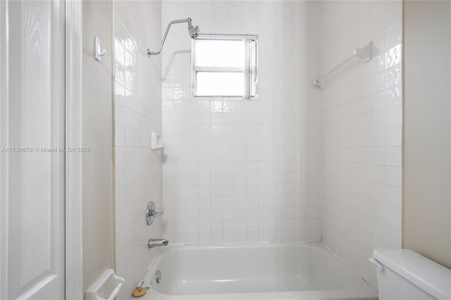 bathroom featuring tiled shower / bath combo and toilet