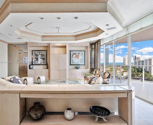 bathroom featuring tile patterned flooring, crown molding, a wall of windows, and a raised ceiling