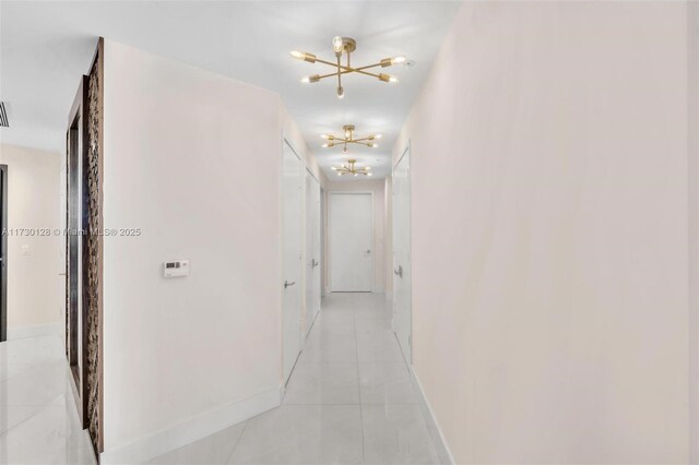 kitchen with a chandelier, island exhaust hood, light tile patterned floors, sink, and white cabinets