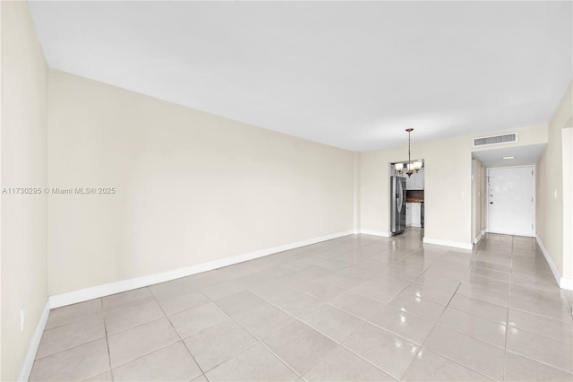 spare room with a notable chandelier and light tile patterned floors