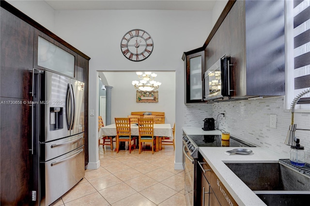 kitchen featuring dark brown cabinets, stainless steel appliances, light tile patterned floors, and decorative backsplash