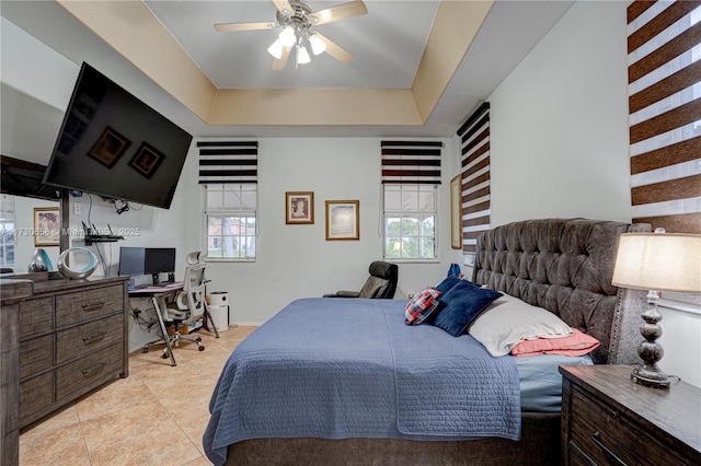 bedroom with a tray ceiling, ceiling fan, and multiple windows