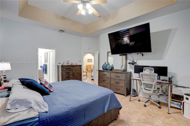 tiled bedroom featuring ceiling fan and a tray ceiling