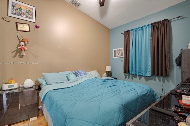 bedroom with ceiling fan, lofted ceiling, and light wood-type flooring