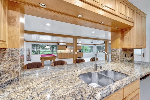 kitchen with tasteful backsplash, a sink, billiards, stainless steel dishwasher, and light stone counters