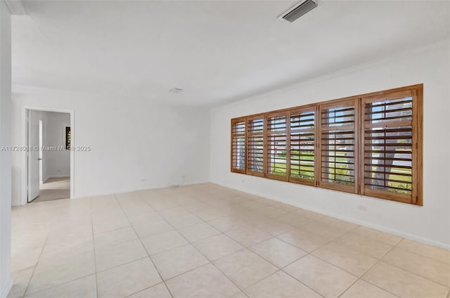 empty room with light tile patterned floors, visible vents, and crown molding