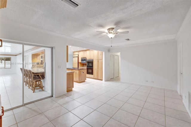 unfurnished living room with a textured ceiling, light tile patterned floors, a ceiling fan, and visible vents