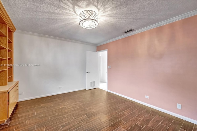 spare room featuring baseboards, ornamental molding, dark wood-style floors, a textured ceiling, and visible vents