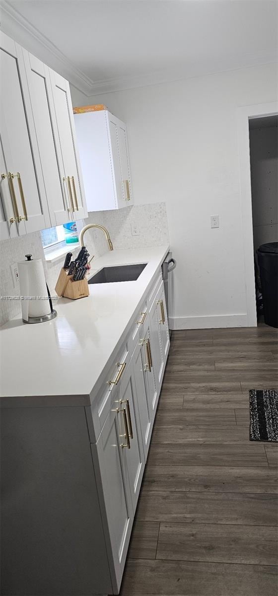 kitchen featuring dark wood-type flooring, sink, white cabinets, and crown molding