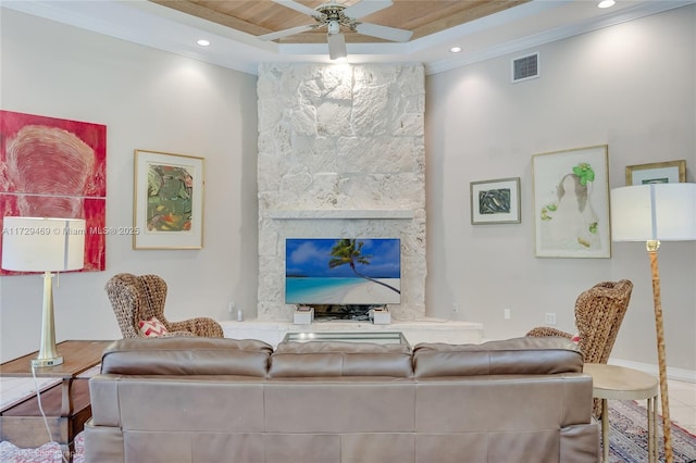 living room featuring a stone fireplace, wood ceiling, ornamental molding, ceiling fan, and a tray ceiling