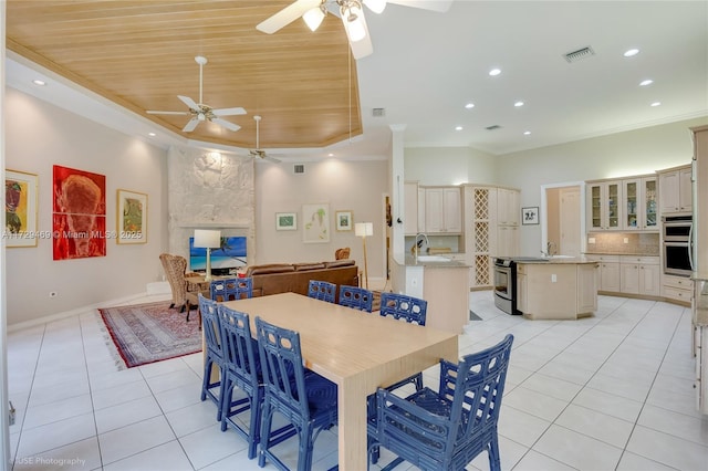 tiled dining room featuring wood ceiling, ceiling fan, a raised ceiling, and crown molding