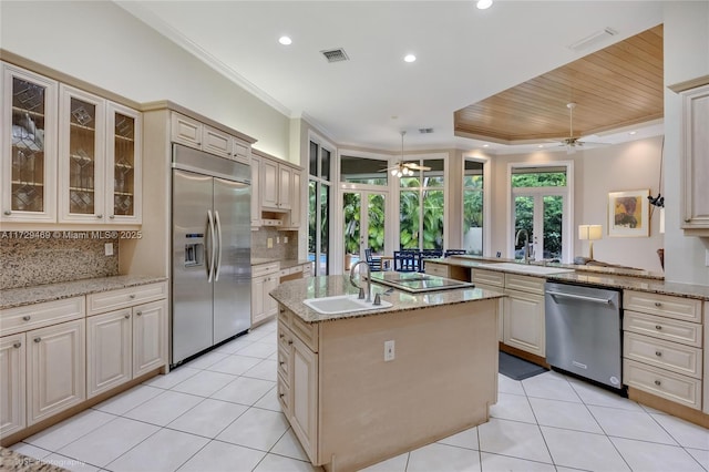 kitchen with stainless steel appliances, decorative backsplash, sink, kitchen peninsula, and a center island with sink