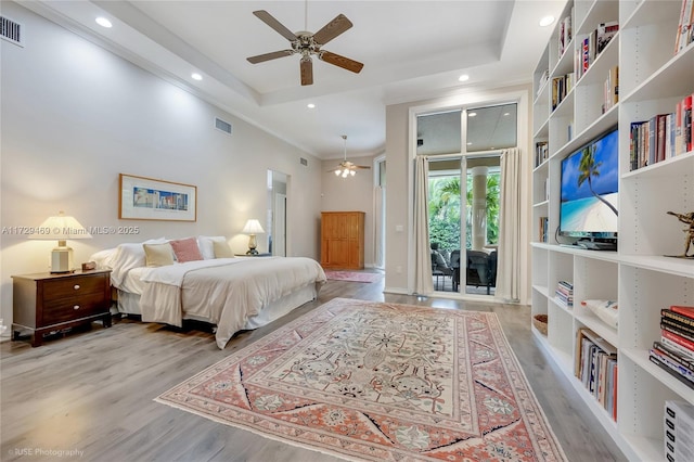 bedroom featuring ceiling fan, a raised ceiling, access to outside, and light hardwood / wood-style flooring