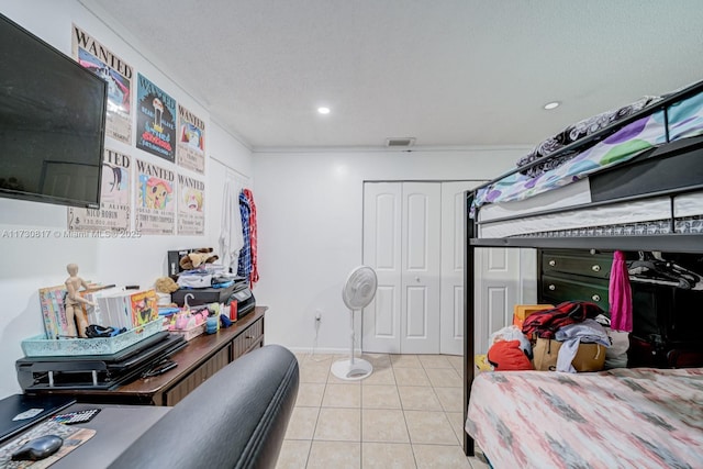 bedroom featuring a textured ceiling, a closet, light tile patterned floors, and ornamental molding