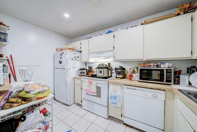 kitchen featuring a textured ceiling, light tile patterned flooring, white appliances, and white cabinetry