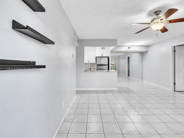 unfurnished living room with sink, ceiling fan, and a textured ceiling