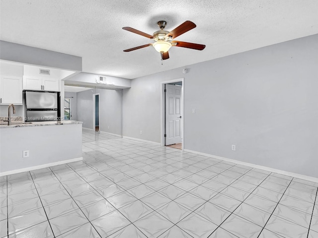 unfurnished living room featuring ceiling fan, sink, and a textured ceiling