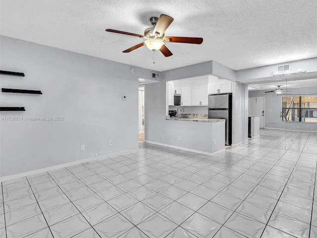 unfurnished living room featuring ceiling fan, sink, and a textured ceiling