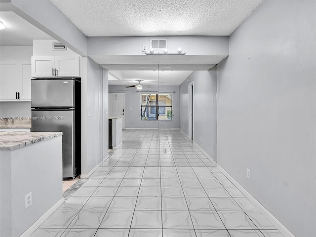 kitchen featuring white cabinets, ceiling fan, a textured ceiling, and stainless steel fridge