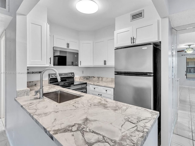 kitchen with white cabinetry, stainless steel refrigerator, sink, kitchen peninsula, and light stone counters