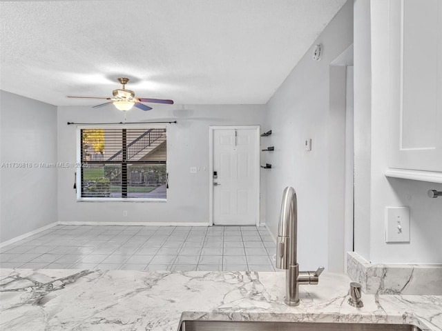 interior space with ceiling fan, sink, a textured ceiling, and white cabinetry