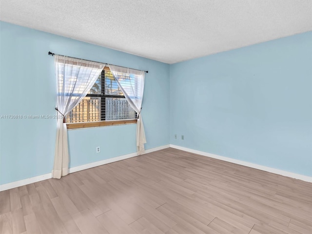 spare room featuring light wood-type flooring and a textured ceiling