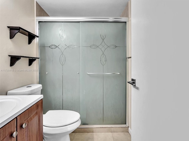 bathroom featuring a shower with shower door, toilet, vanity, and tile patterned flooring