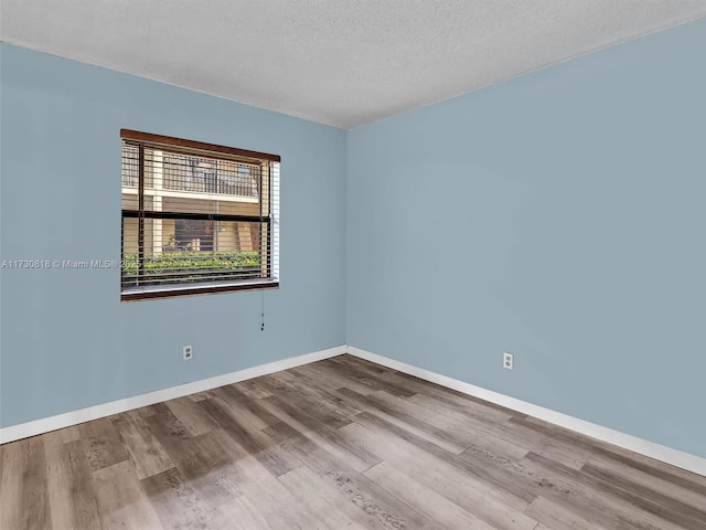 unfurnished room with a textured ceiling and light hardwood / wood-style flooring