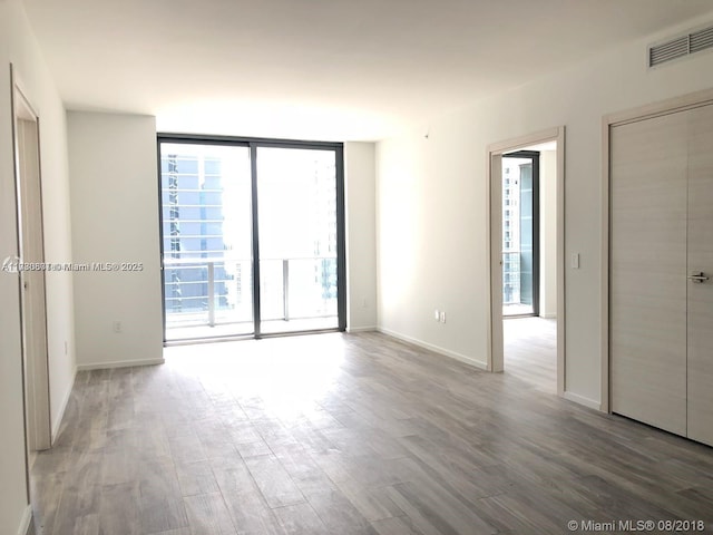 empty room with hardwood / wood-style flooring and a wall of windows