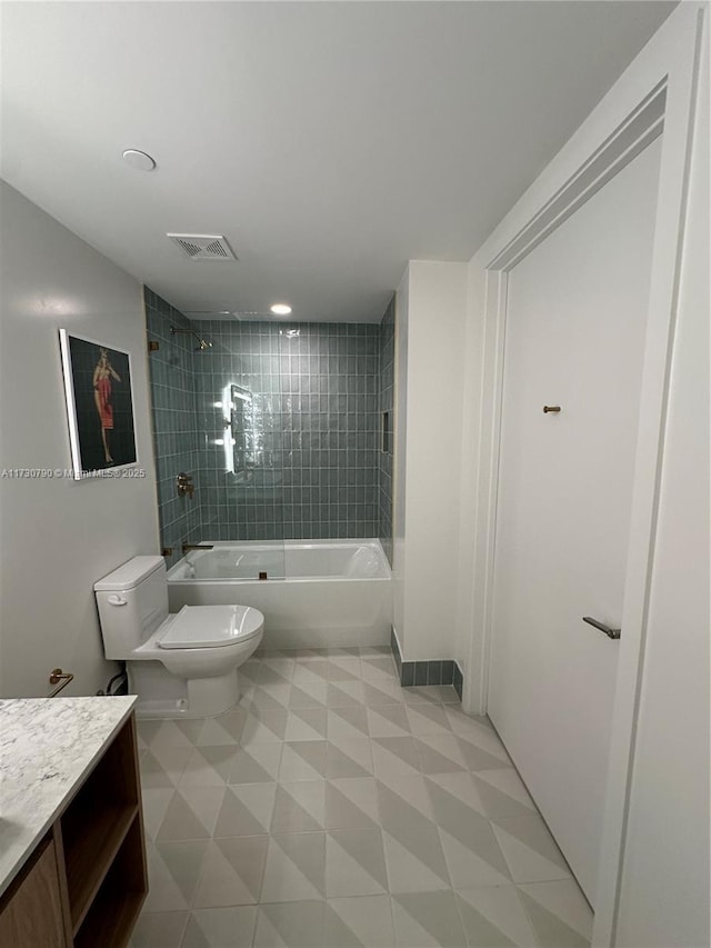 full bathroom featuring tiled shower / bath, vanity, and toilet