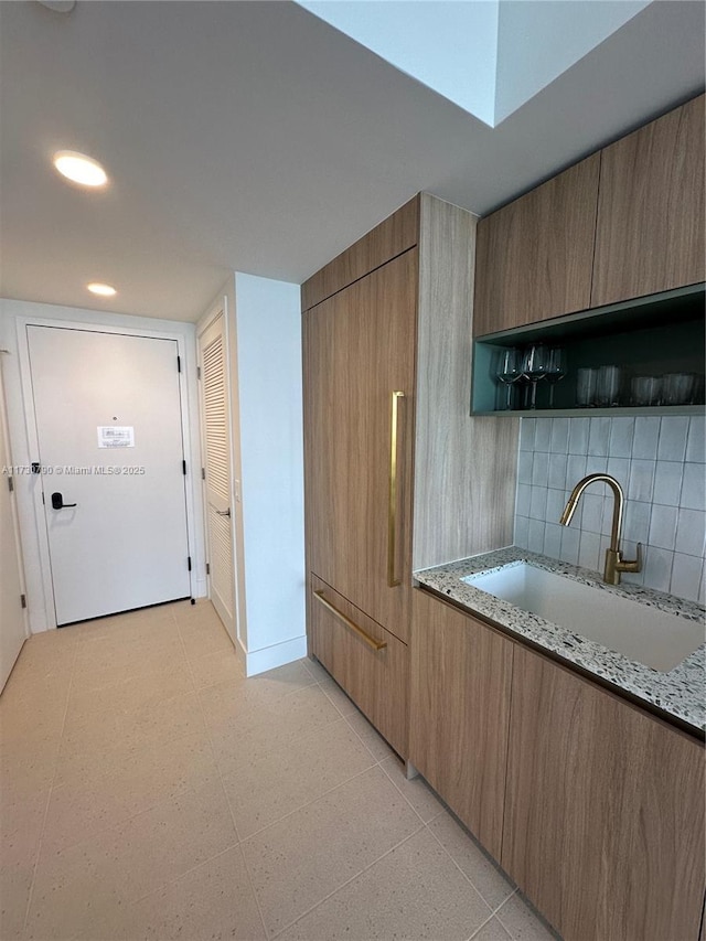 kitchen with light stone countertops, sink, and backsplash