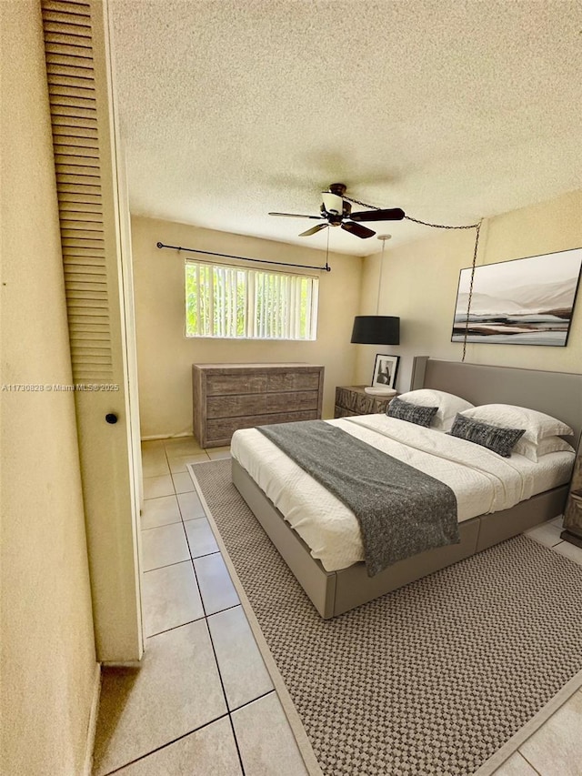 bedroom featuring light tile patterned flooring, a textured ceiling, and ceiling fan