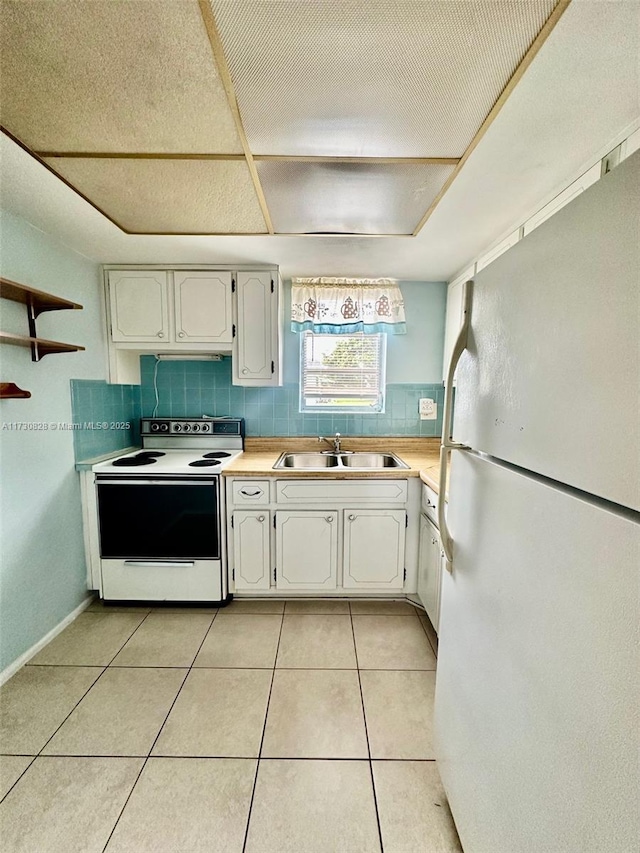 kitchen featuring sink, white cabinetry, white appliances, and light tile patterned floors