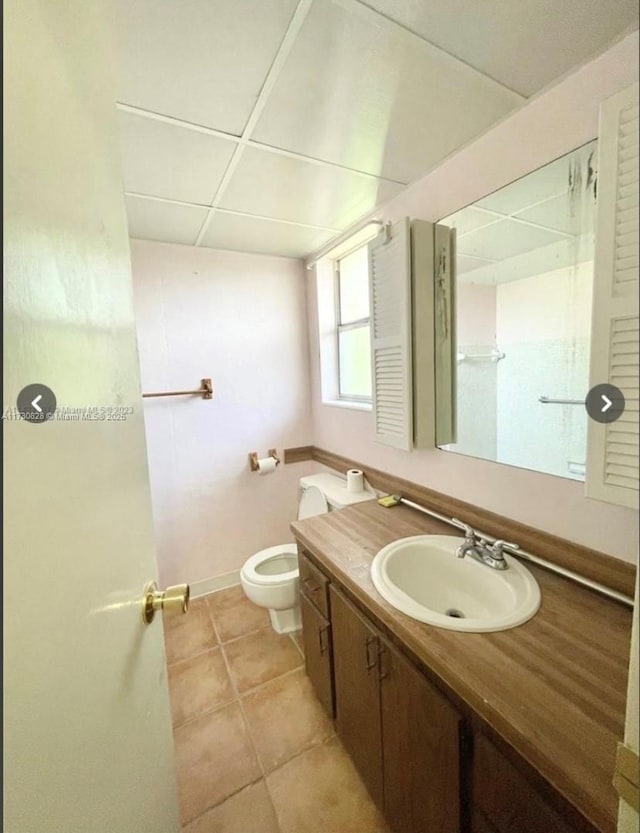 bathroom with vanity, toilet, a paneled ceiling, and tile patterned flooring