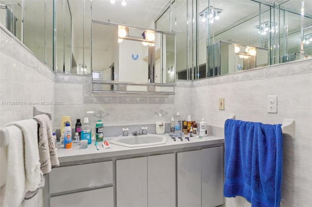 bathroom featuring tile walls, vanity, backsplash, and a textured ceiling