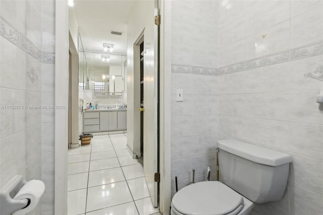 bathroom with tile patterned flooring, vanity, tile walls, and toilet