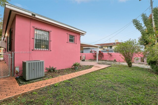 view of side of home featuring a patio, a yard, and central AC