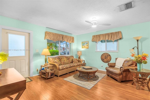 living room with a textured ceiling, a healthy amount of sunlight, light hardwood / wood-style flooring, and ceiling fan