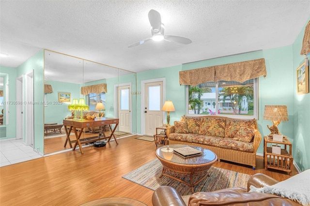 living room featuring a textured ceiling, light hardwood / wood-style flooring, and ceiling fan