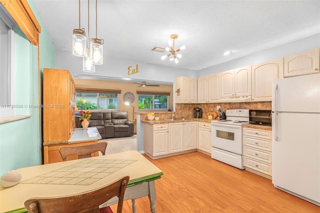 kitchen with kitchen peninsula, pendant lighting, white appliances, a textured ceiling, and decorative backsplash